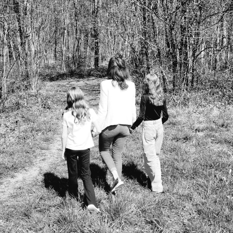 Familientherapie Mutter mit zwei Kindern läuft einen Waldweg entlang in einem Schwarzweiß-Foto